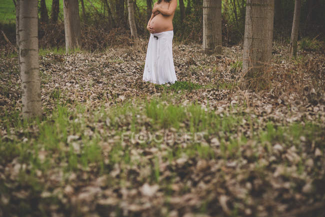 Crop topless woman hiding breast and embracing belly — Stock Photo
