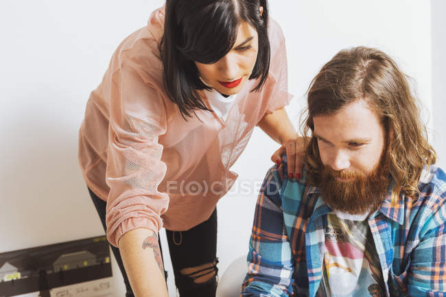 Mujer con la mano en el hombro del hombre y mirando en la mesa - foto de stock