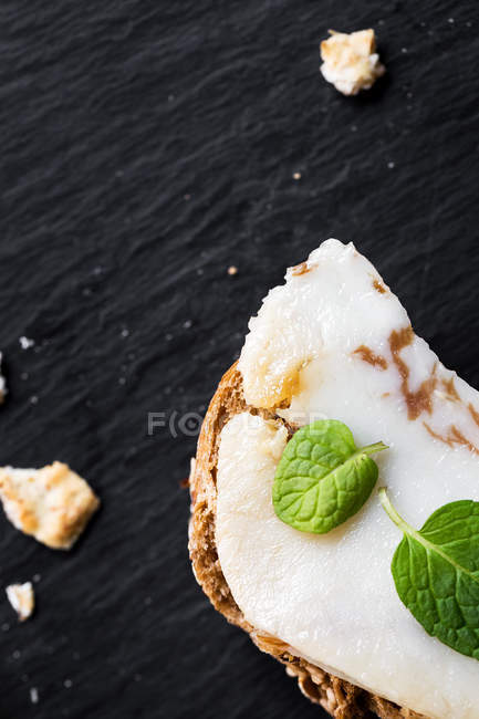 Сэндвич с солоноватым беконом и мятными листьями на доске — стоковое фото