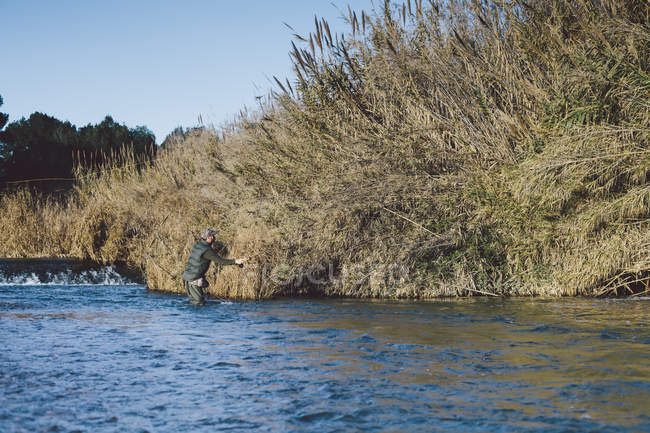 Vista posteriore della pesca del pescatore con canna al fiume di campagna — Foto stock