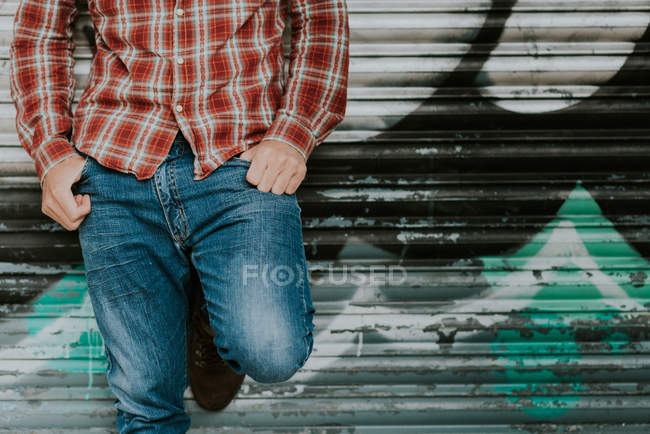 Ansicht des Mannes im karierten Hemd, der sich an eine Graffiti-Wand lehnt — Stockfoto