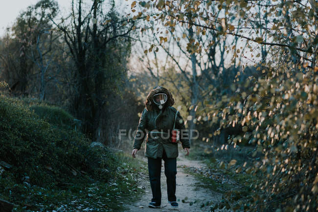 Retrato del hombre con máscara de gas y caminando por el camino rural - foto de stock