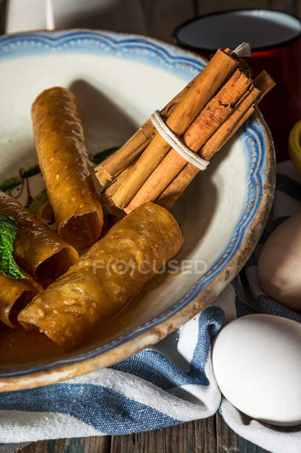 Close up view of late with fried honey tough tubes and cinnamon sticks on towell — стоковое фото