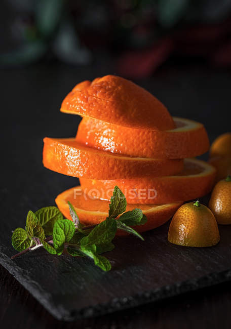 Orange fraîche tranchée avec des feuilles de menthe sur ardoise — Photo de stock