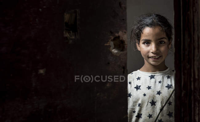 Арабських дівчинка, дивлячись на камеру через отвір в руїнах — стокове фото