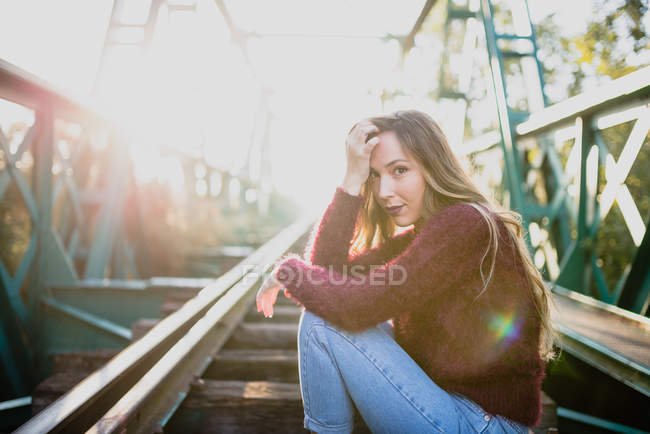 Girl sitting on rail and looking at camera. — Stock Photo