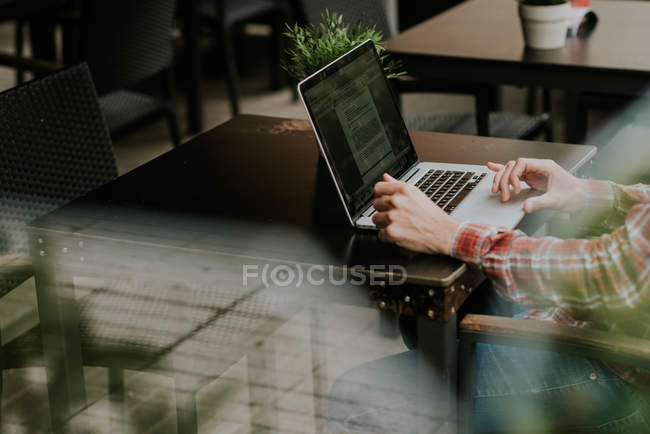 Cropped image of male hands using laptop at cafe terrace table — Stock Photo