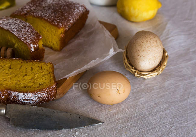 Close up view of eggs with lemon cake slices on rural tablecloth — Stock Photo