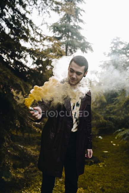 Портрет молодого чоловіка, який позує з димом у лісі — стокове фото