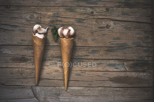 Directly above two waffle cones with garlic coves on rural table — Stock Photo