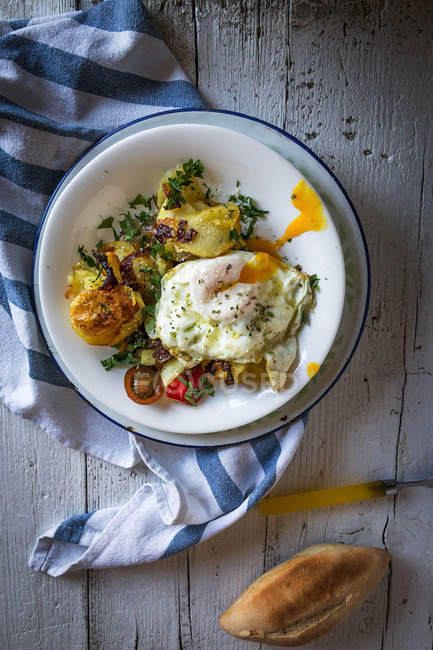 Безпосередньо над тарілкою зі смаженим яйцем та картоплею у сільській тарілці на рушнику — стокове фото