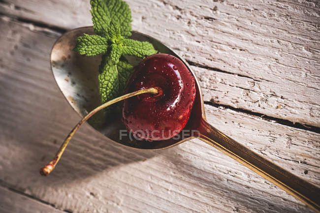 Close up view of spoon with cherry and mint leaves — Stock Photo