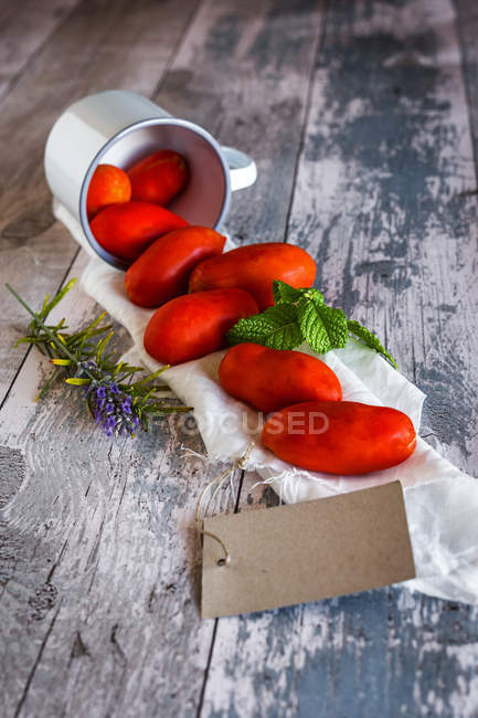 Tomates et feuilles de menthe sur serviette rurale — Photo de stock