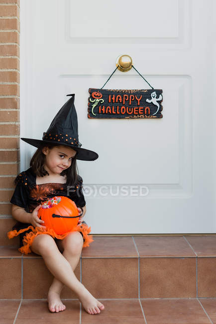 Ragazza in costume da strega seduta sul portico — Foto stock