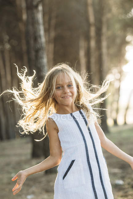 Schönes Kind wedelt im Sonnenlicht mit Haaren und blickt in die Kamera — Stockfoto