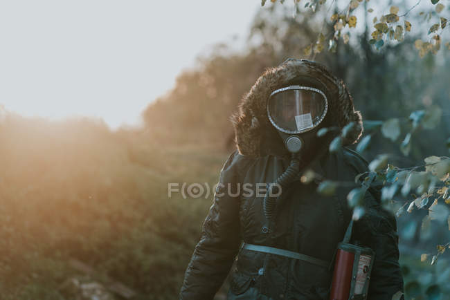 Portrait of man wearing gas mask walking at countryside field — Stock Photo
