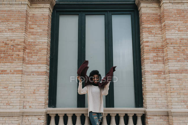 Ritratto di ragazza sorridente in posa con sciarpa sopra vecchio muro di mattoni sullo sfondo — Foto stock