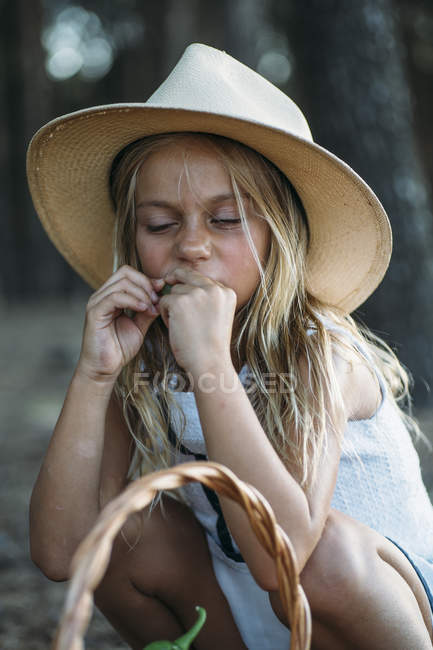 Дитина в капелюсі їсть фрукти з кошика — стокове фото