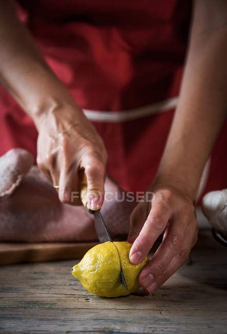 Gros plan de femme coupe citron pour presser sur le poulet cru — Photo de stock