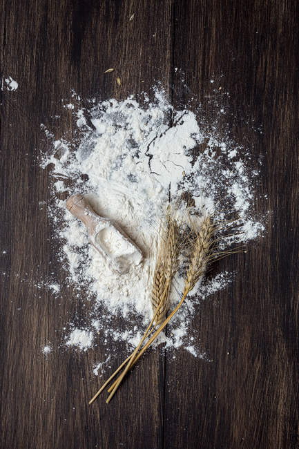 Flour and wheat spikes on rural wooden table — Stock Photo