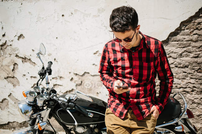 Чоловік спирається на велосипед і використовує смартфон — стокове фото