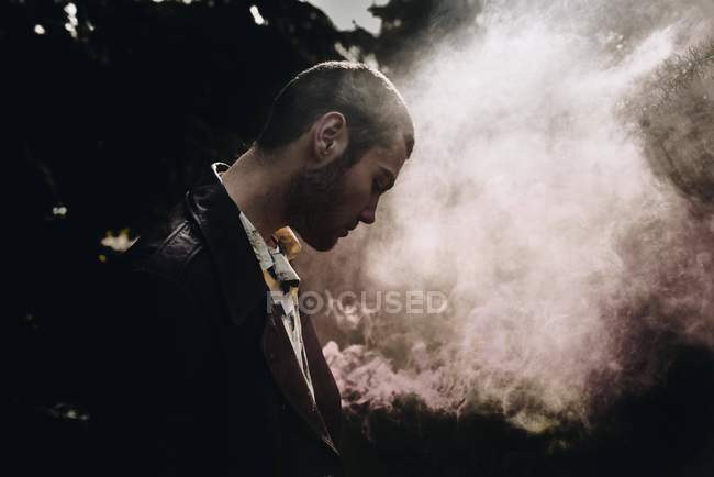 Вид збоку чоловіка позує з димом свічкою в лісі — стокове фото