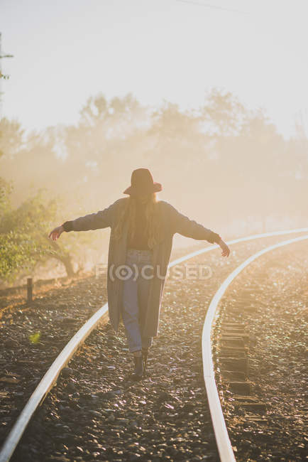 Chica caminando en los ferrocarriles - foto de stock