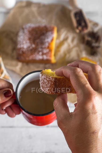 Vista superior de las manos femeninas sosteniendo taza de chocolate caliente y rebanada de pastel casero - foto de stock