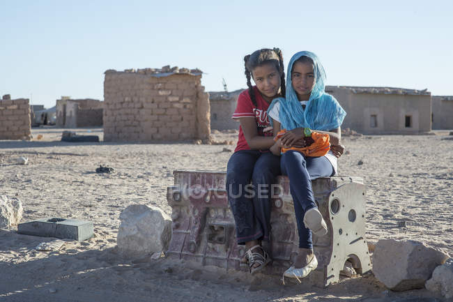 Rabische Mädchen, die in die Kamera schauen und auf Stein sitzen — Stockfoto