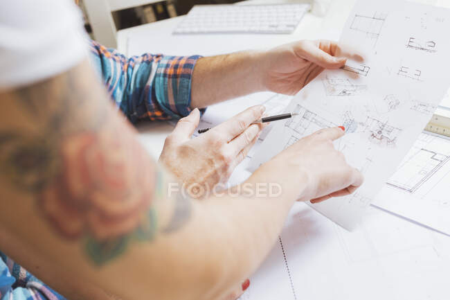 Male hands showing blueprints during female hand pointing — Stock Photo