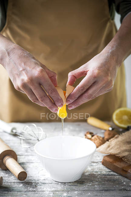 Seção média do ovo rachando fêmea na tigela na mesa de madeira — Fotografia de Stock
