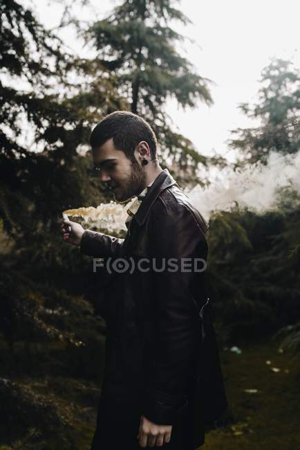 Человек позирует в лесу с дымовой свечой . — стоковое фото