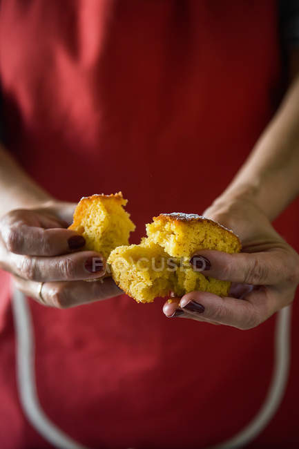 Sección media de hembra rasgando rodaja de pastel de limón - foto de stock