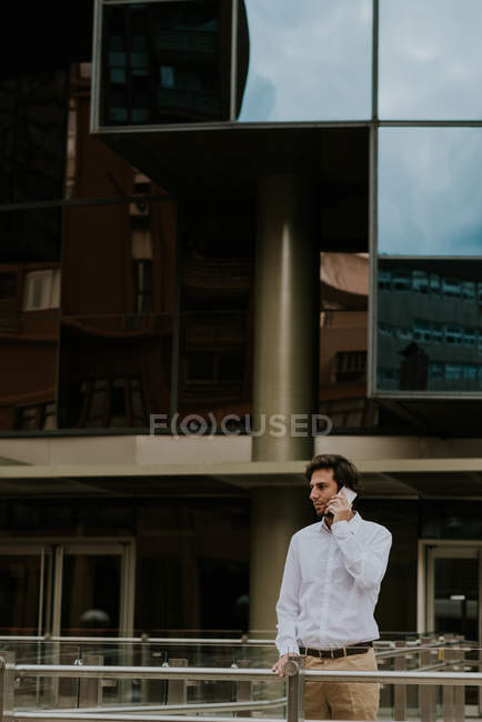 Retrato de hombre de negocios confiado en hablar en el teléfono inteligente en la escena urbana del centro - foto de stock