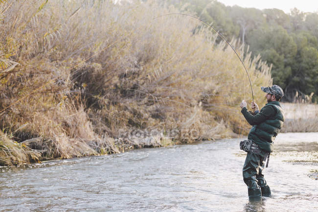 Side view of fisher fishing in country river — Stock Photo