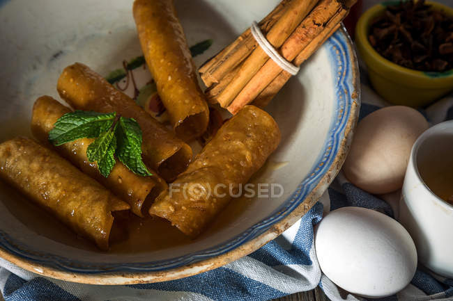 Vue rapprochée de l'assiette avec tubes de pâte au miel frit et bâtonnets de cannelle sur serviette — Photo de stock