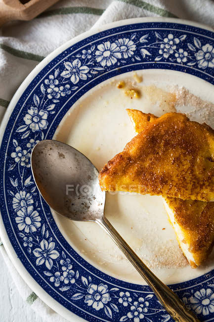 Top view of ceramic ornate plate with sweet toasts and spoon on towel — Stock Photo