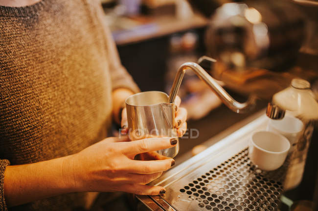 Crop hands beating up cream for cappuccino with coffee machine steamer — Stock Photo