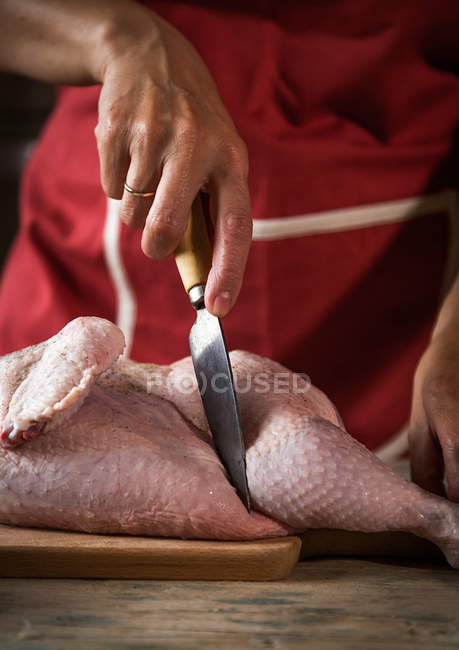 Close-up de mulher corte de frango cru na placa de madeira — Fotografia de Stock