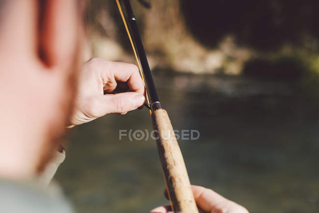 Mãos de colheita ajustando haste de pesca no rio — Fotografia de Stock