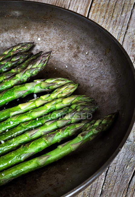 Crop fried asparagus sprouts in plate on rural table — Stock Photo