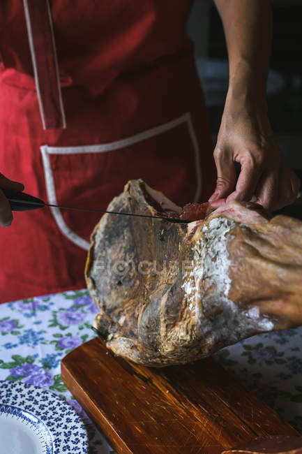 Femme méconnaissable tranchant du jambon tranché — Photo de stock