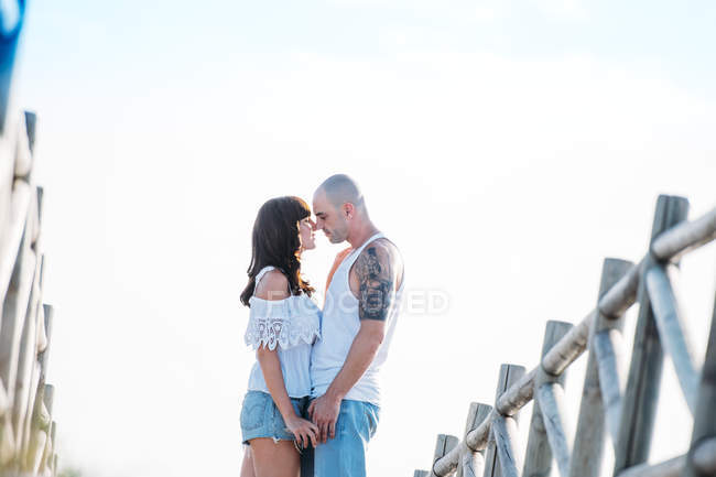 Пара стоїть обличчям до неба біля дерев'яного мосту — стокове фото