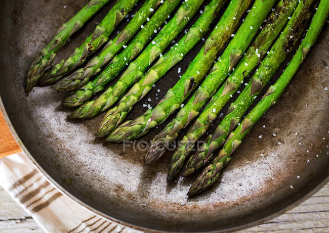 Crop asparagus stems in frying pan — Stock Photo