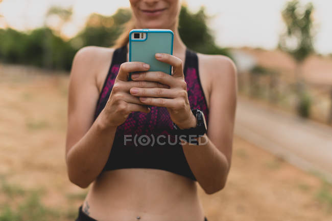 Sportswoman utilisant son smartphone dans le parc après l'entraînement — Photo de stock