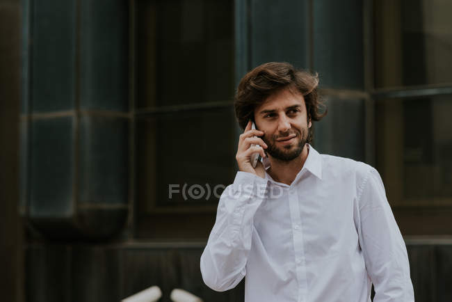 Retrato de empresário confiante em camisa branca falando no smartphone no centro da cidade cena urbana — Fotografia de Stock