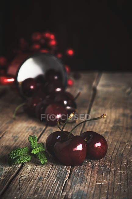 Cerejas frescas maduras espalhadas em madeira escura — Fotografia de Stock