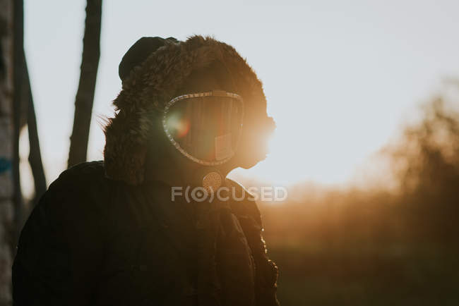 Portrait of man wearing coat hood with gas mask on face standing in countryside field — Stock Photo