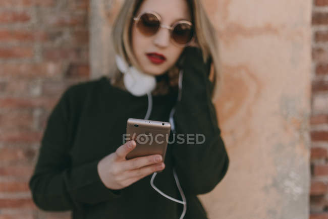 Дівчина тримає смартфон і слухає музичні навушники — стокове фото