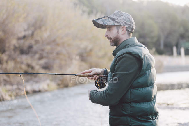 Side view of fisher with rod at river shore — Stock Photo